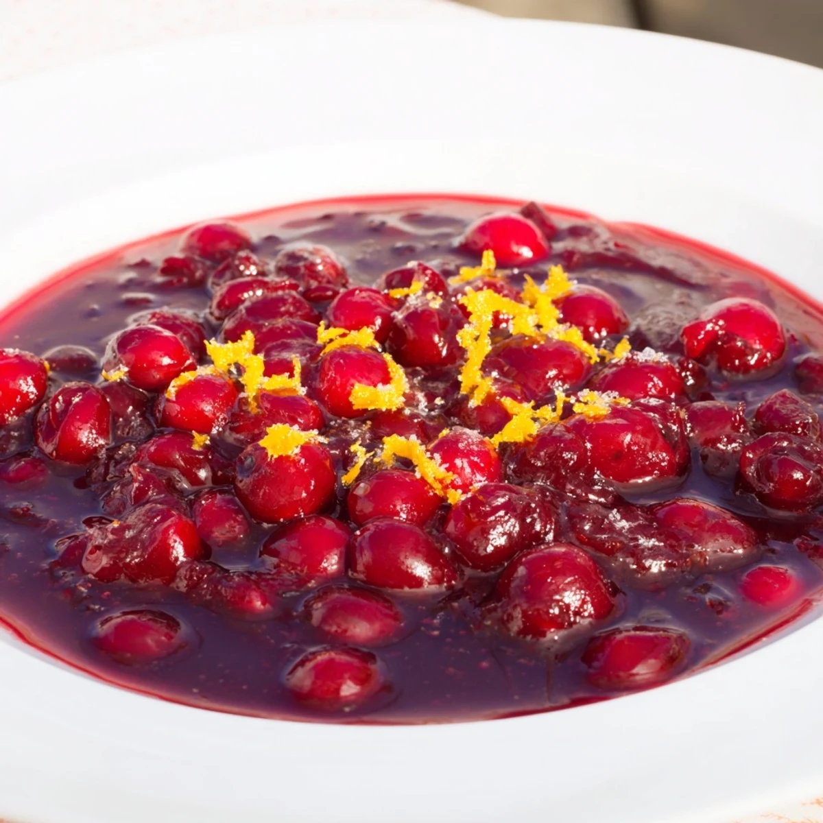 Vibrant red cranberry topping sauce, perfect for desserts, looks thick and rich in the photo.