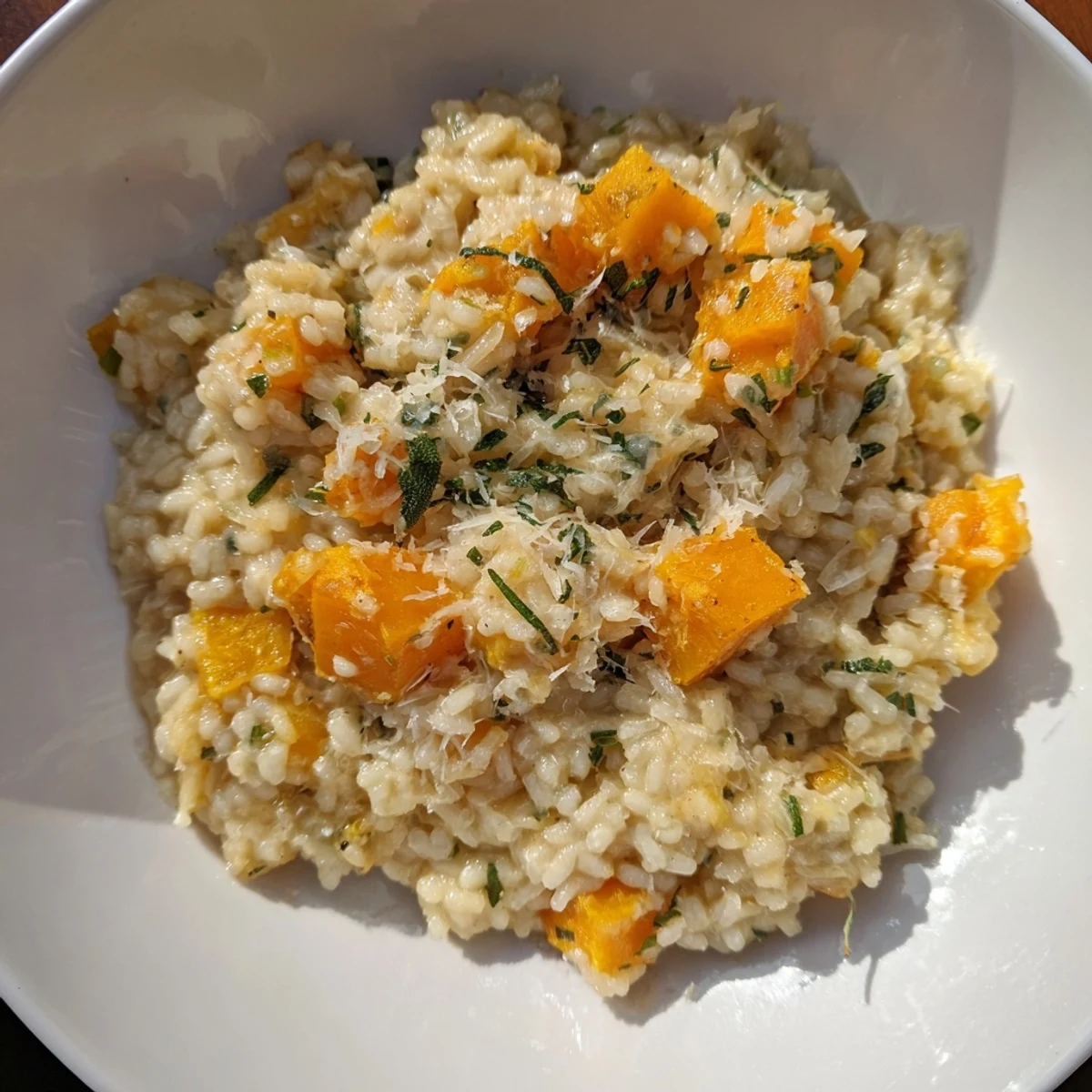 A bowl overflowing with comforting butternut squash risotto, its aroma fragrant with fresh Parmesan cheese.