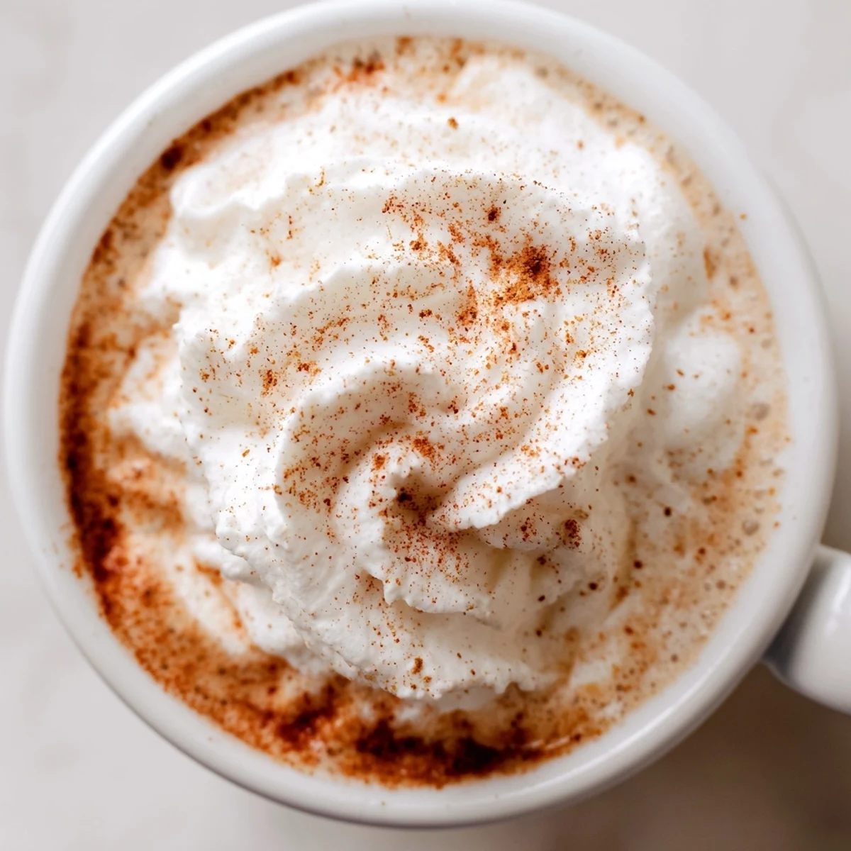 Steaming Gingerbread Lattes topped with whipped cream and cinnamon; a festive holiday beverage.