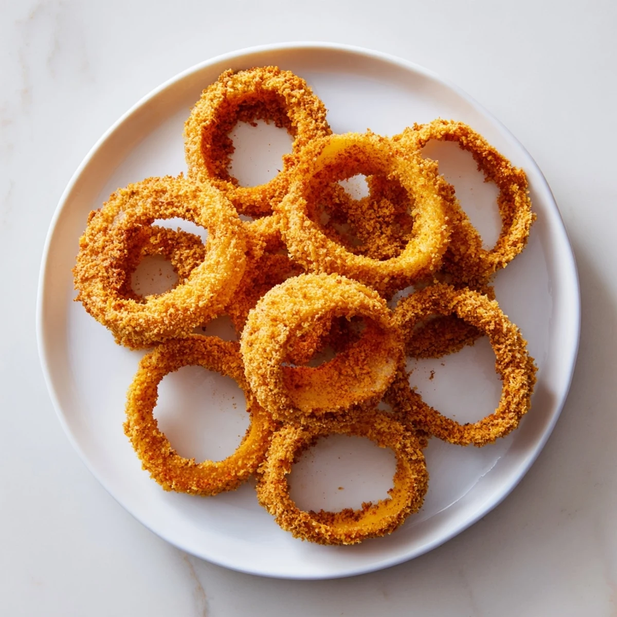 Golden-brown baked onion rings piled high, perfect crispy appetizers on a serving plate.