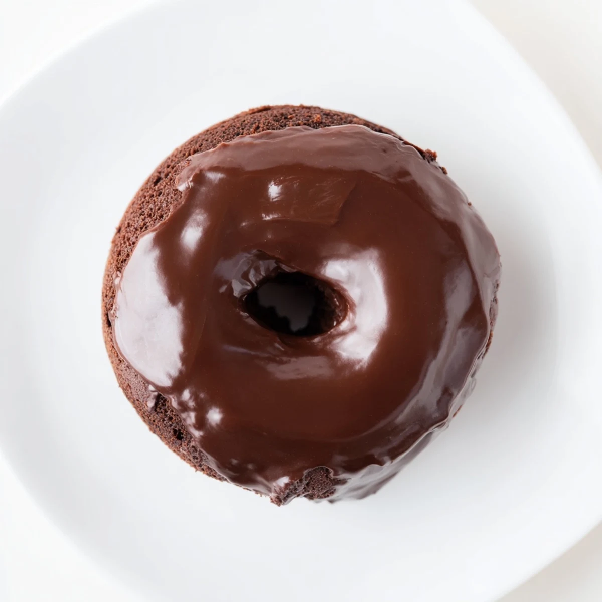 Freshly baked chocolate donuts, still glistening from a silky smooth chocolate glaze, ready to serve.