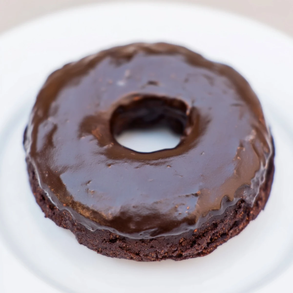 Warm, glazed chocolate donuts arranged enticingly on a cooling rack for a sweet treat.
