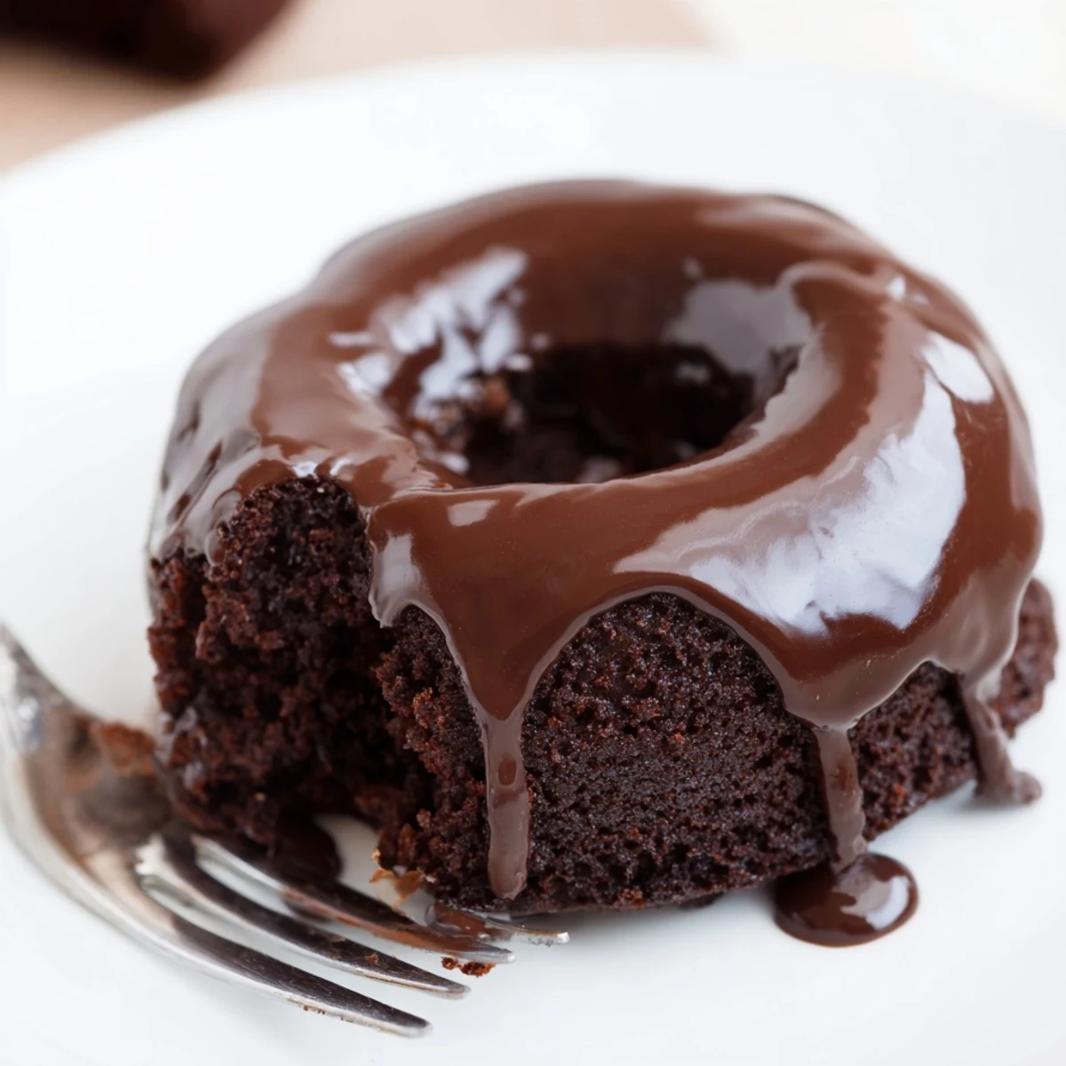 Freshly baked chocolate donut with glaze topped with colorful sprinkles on a wire cooling rack.