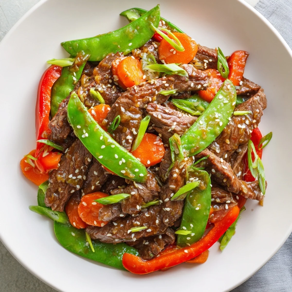 A hot wok holds freshly cooked Beef Stir Fry with Snow Peas and Carrots, tossed in glossy, savory sauce ready to be served over steamed white rice.