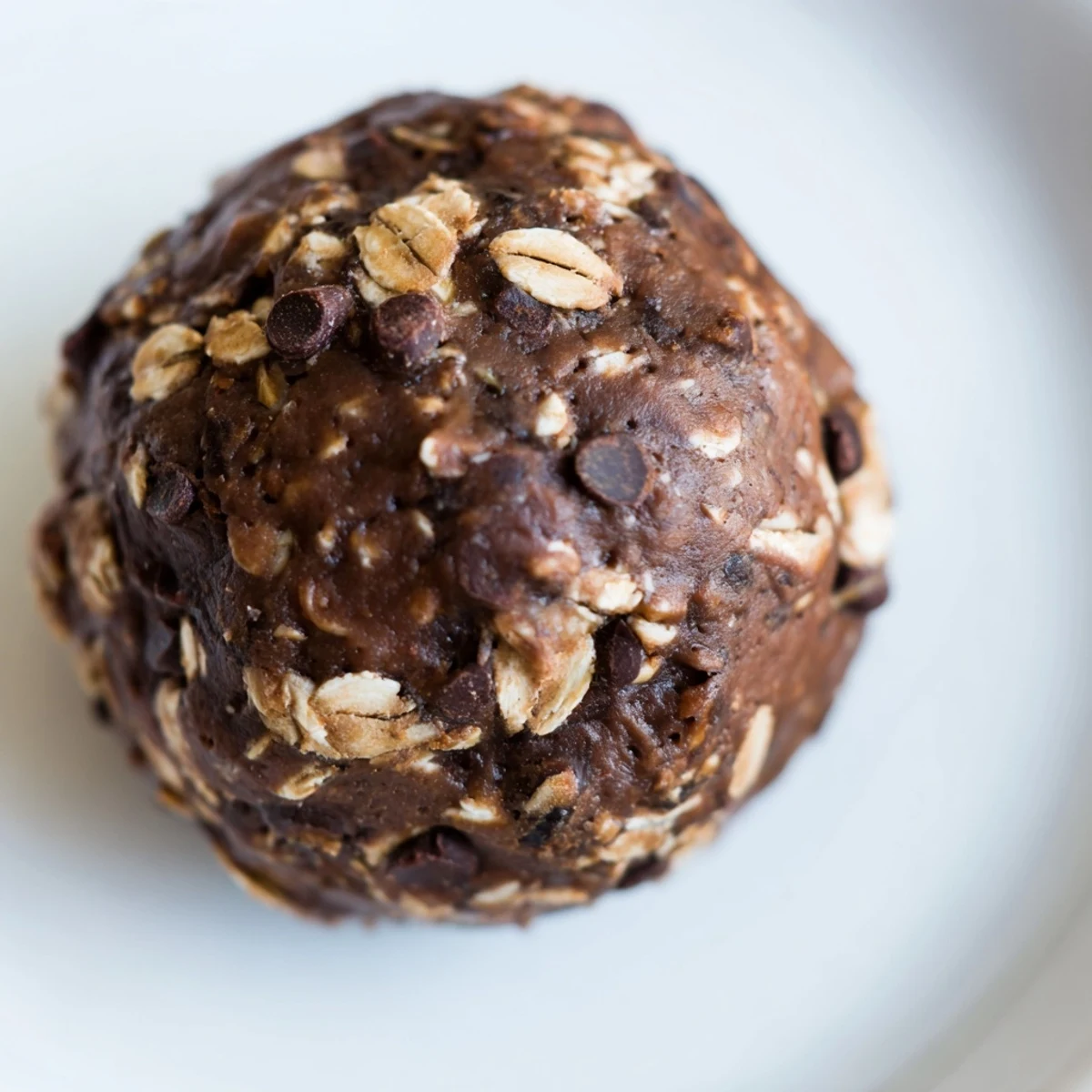 Freshly rolled Chocolate Peanut Butter Energy Balls with oats, cocoa, and mini chocolate chips on a parchment-lined tray.