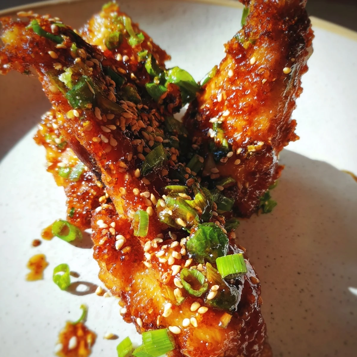 Golden-brown Big Game Sticky Honey Garlic Wings rest on a platter, glossy with sweet glaze and sprinkled with sesame seeds and green onions.  