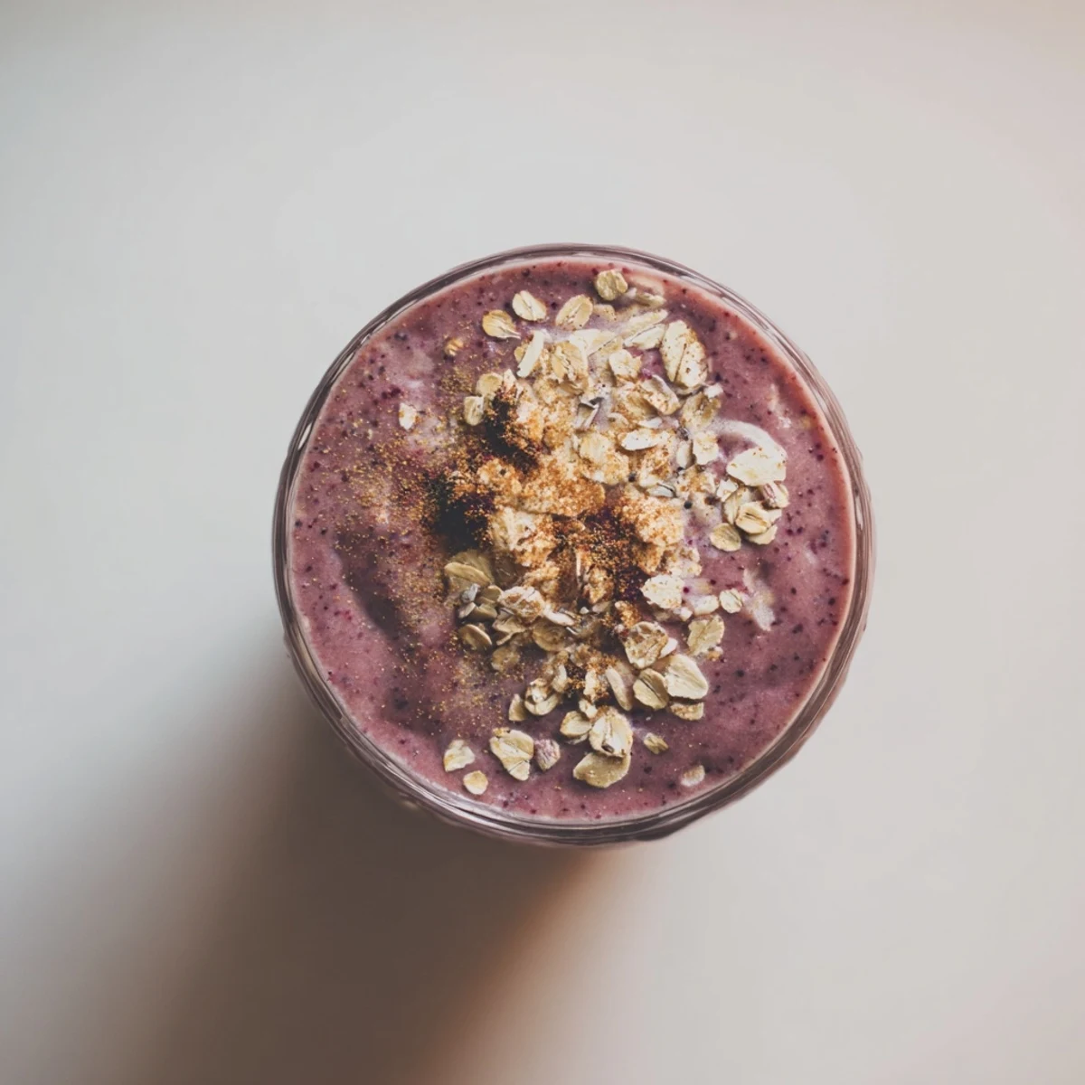 A frosty glass of Winter Smoothie Blend with Berries, topped with fresh berries and a sprinkle of cinnamon.