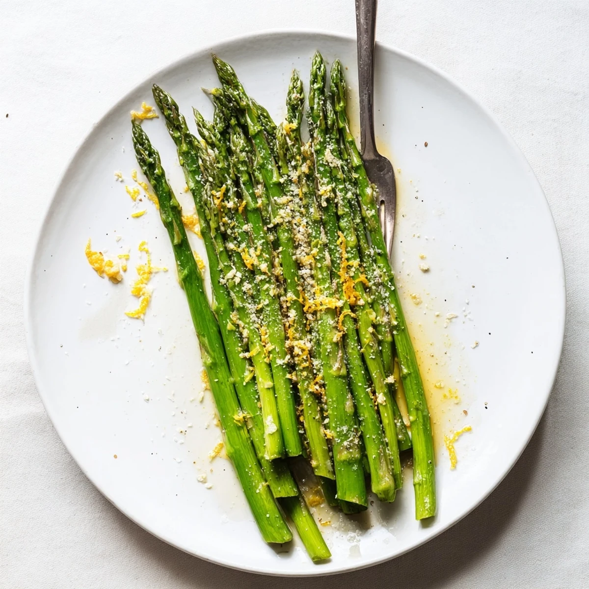 Vibrant green Lemon Garlic Asparagus with Parmesan fresh from the skillet, garnished with extra lemon zest and cheese shavings.