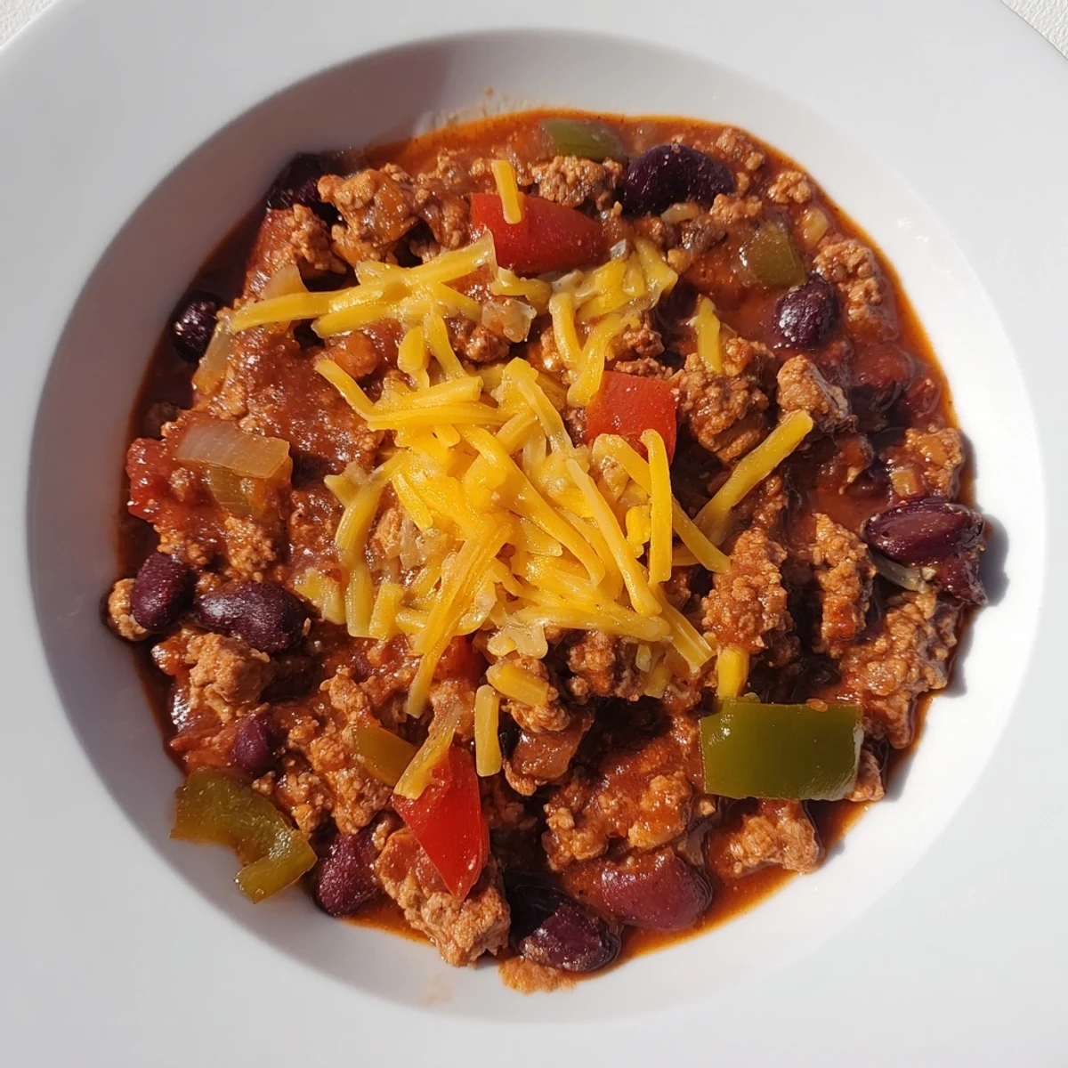 Touchdown Turkey Chili with Cheddar Cheese bubbling in a Dutch oven, steam rising with a bold, spicy aroma.