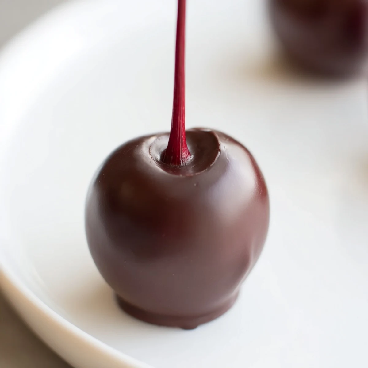 Bright red maraschino cherries with stems are fully encased in creamy fondant and dipped in dark chocolate for these homemade Chocolate Covered Cherries.