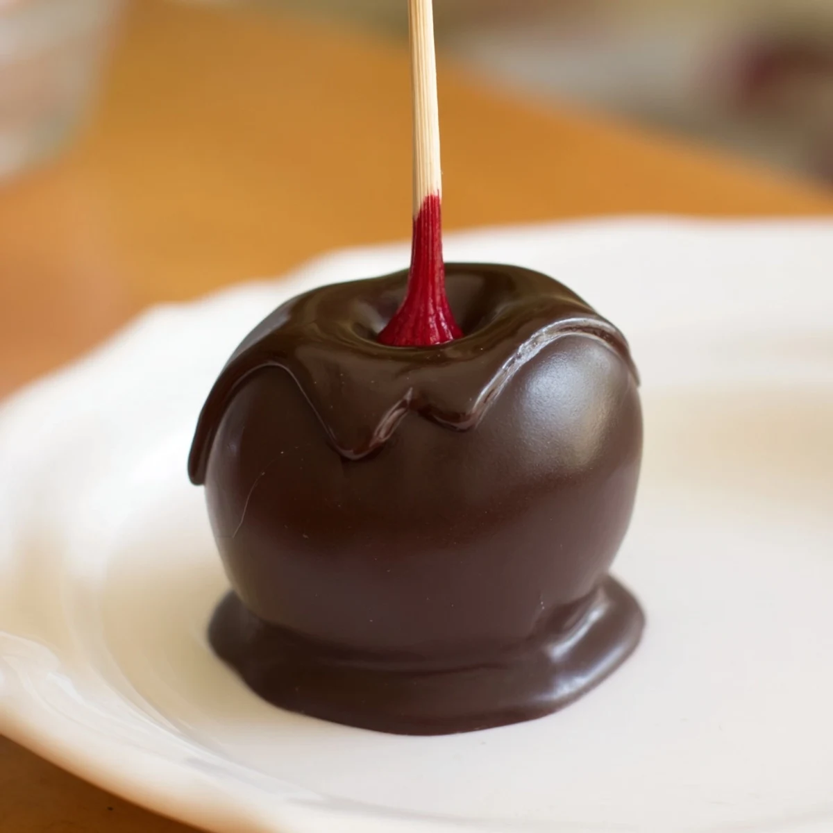 Decadent Chocolate Covered Cherries with a liquid center, glistening under soft light as a hand reaches for one bite.