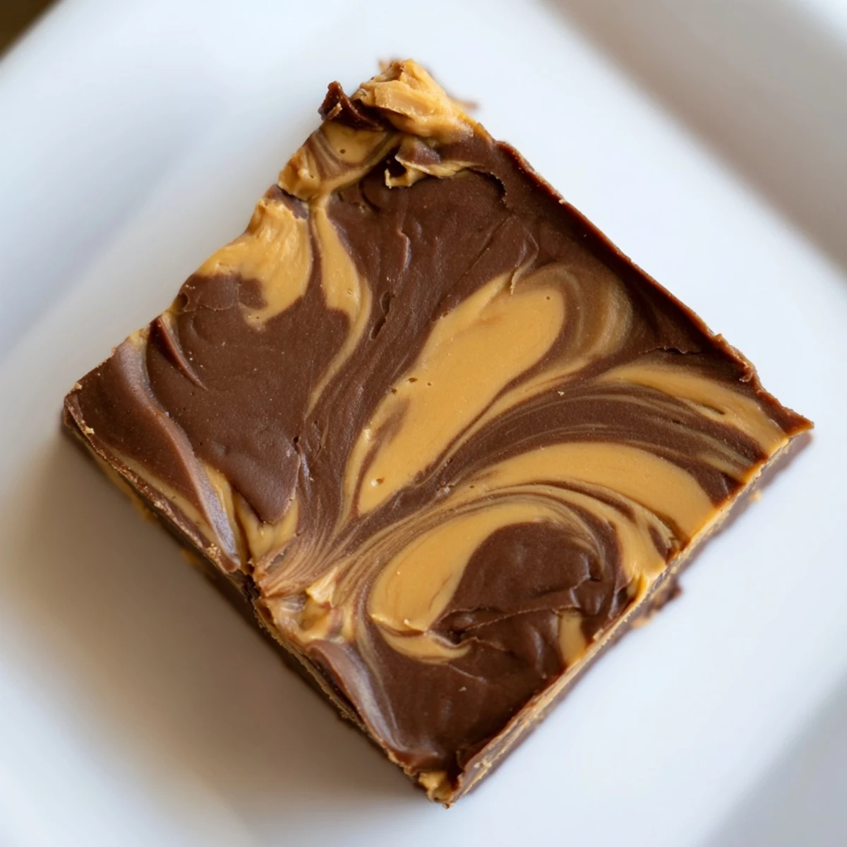 Fudgy squares of Chocolate Peanut Butter Fudge, with a rich melted chocolate base and creamy swirls for dessert.
