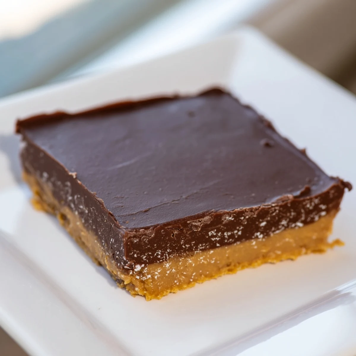 A close-up view of Chocolate Peanut Butter Fudge Squares with a smooth chocolate top, ready to serve at a party.