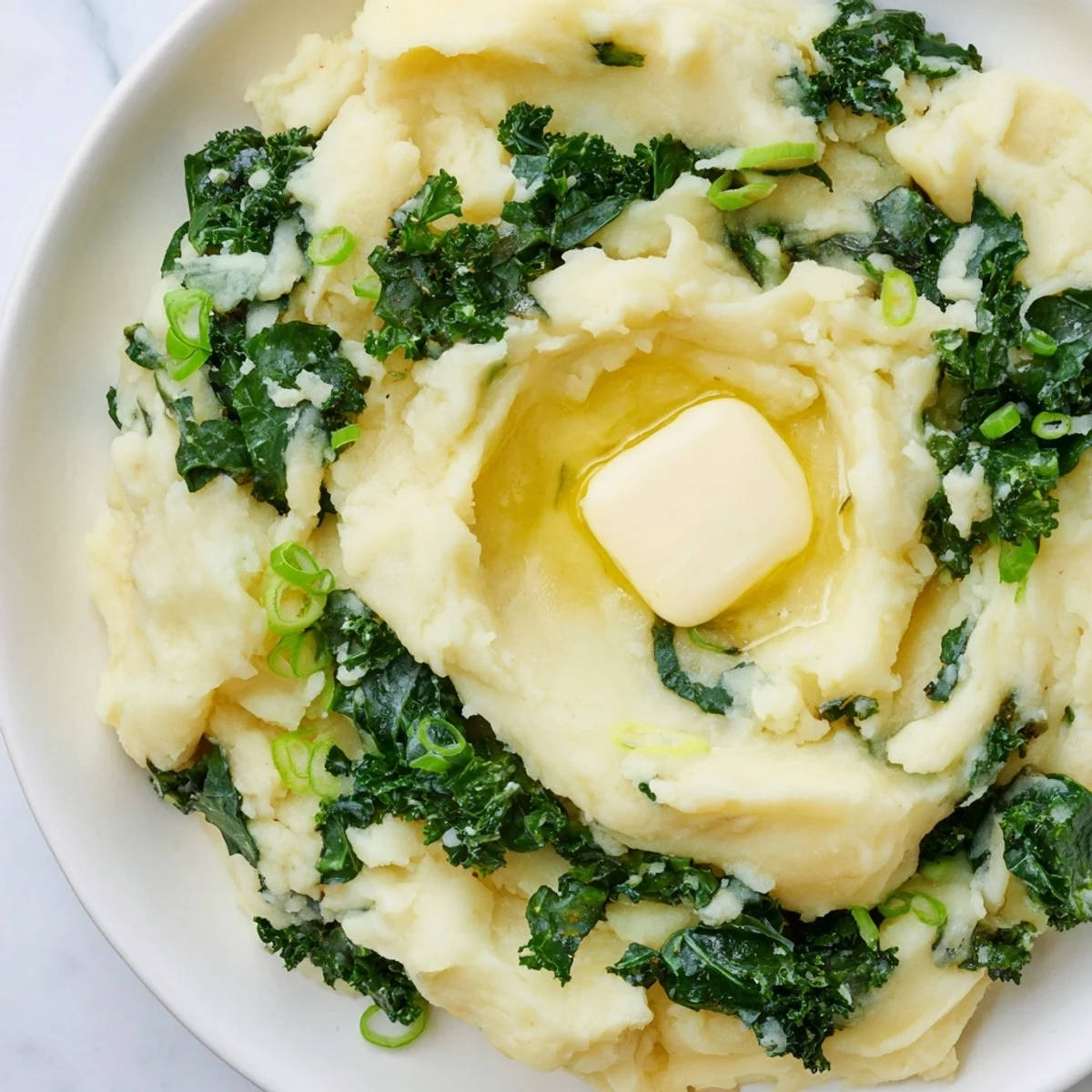 A hearty bowl of Irish Colcannon with Kale and Butter garnished with sliced scallions, served warm for comfort.
