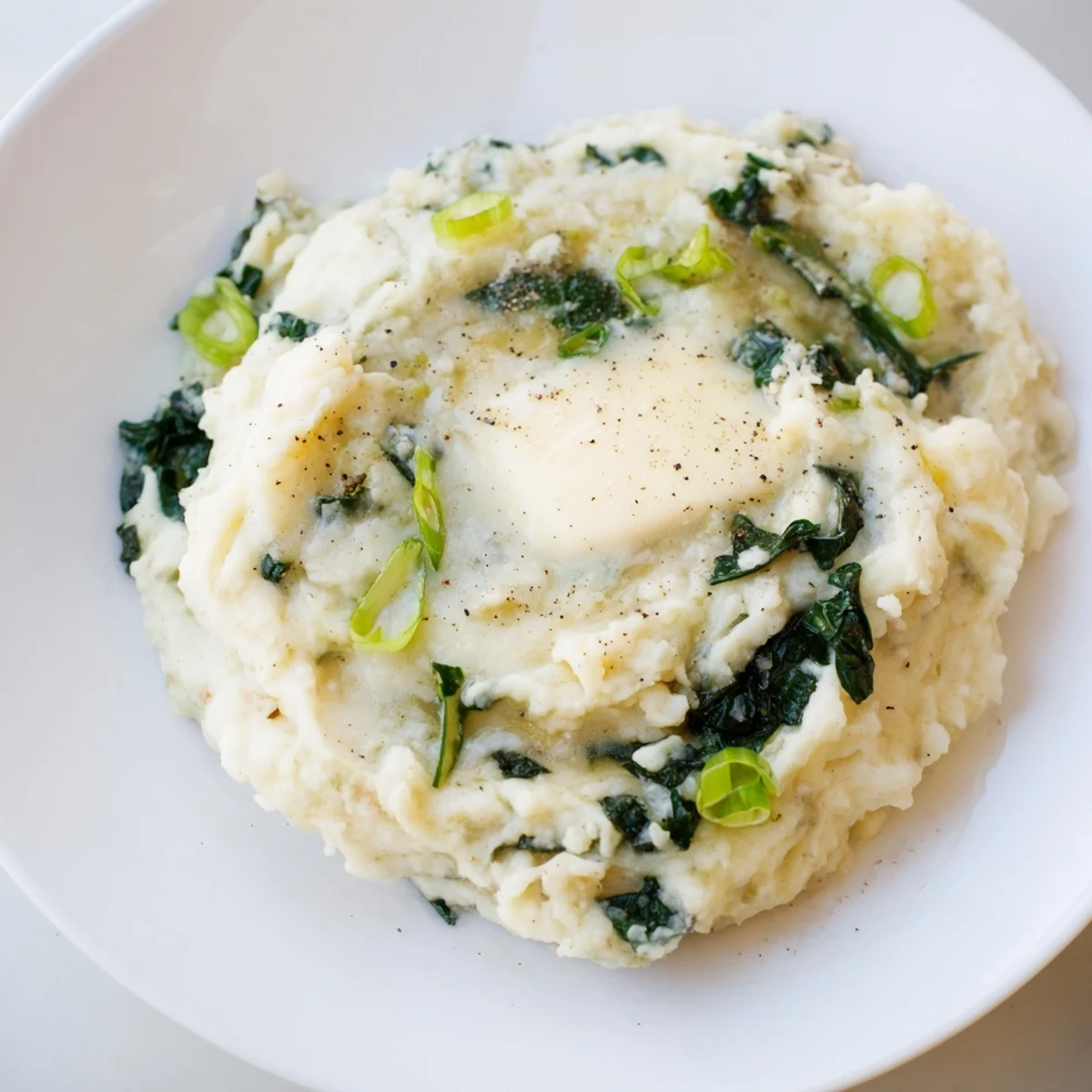 Irish Colcannon with Kale and Butter served hot, topped with a pat of butter alongside sautéed kale and potatoes.