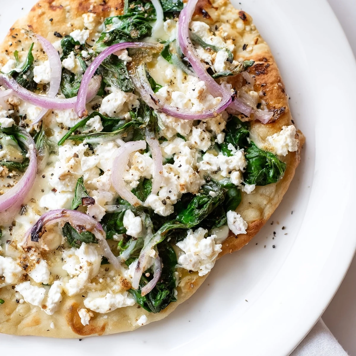 Freshly baked Spinach and Feta Flatbread Pizza with golden crust and melted cheese on a rustic table.