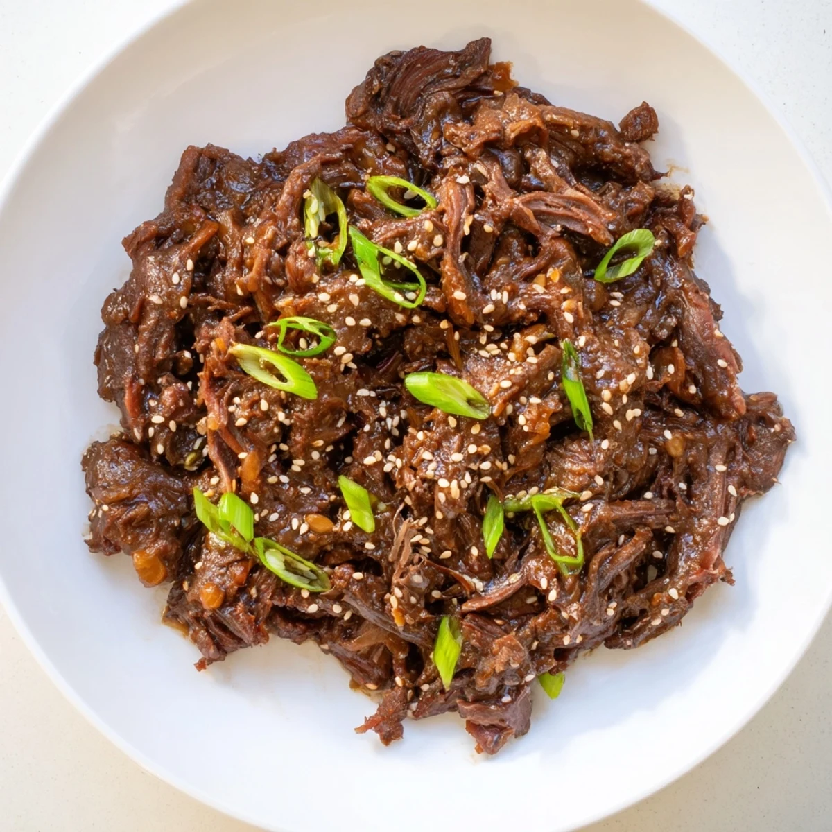 Steaming hot Crock Pot Korean Beef over rice in a ceramic bowl, surrounded by ingredients like pear and gochujang.