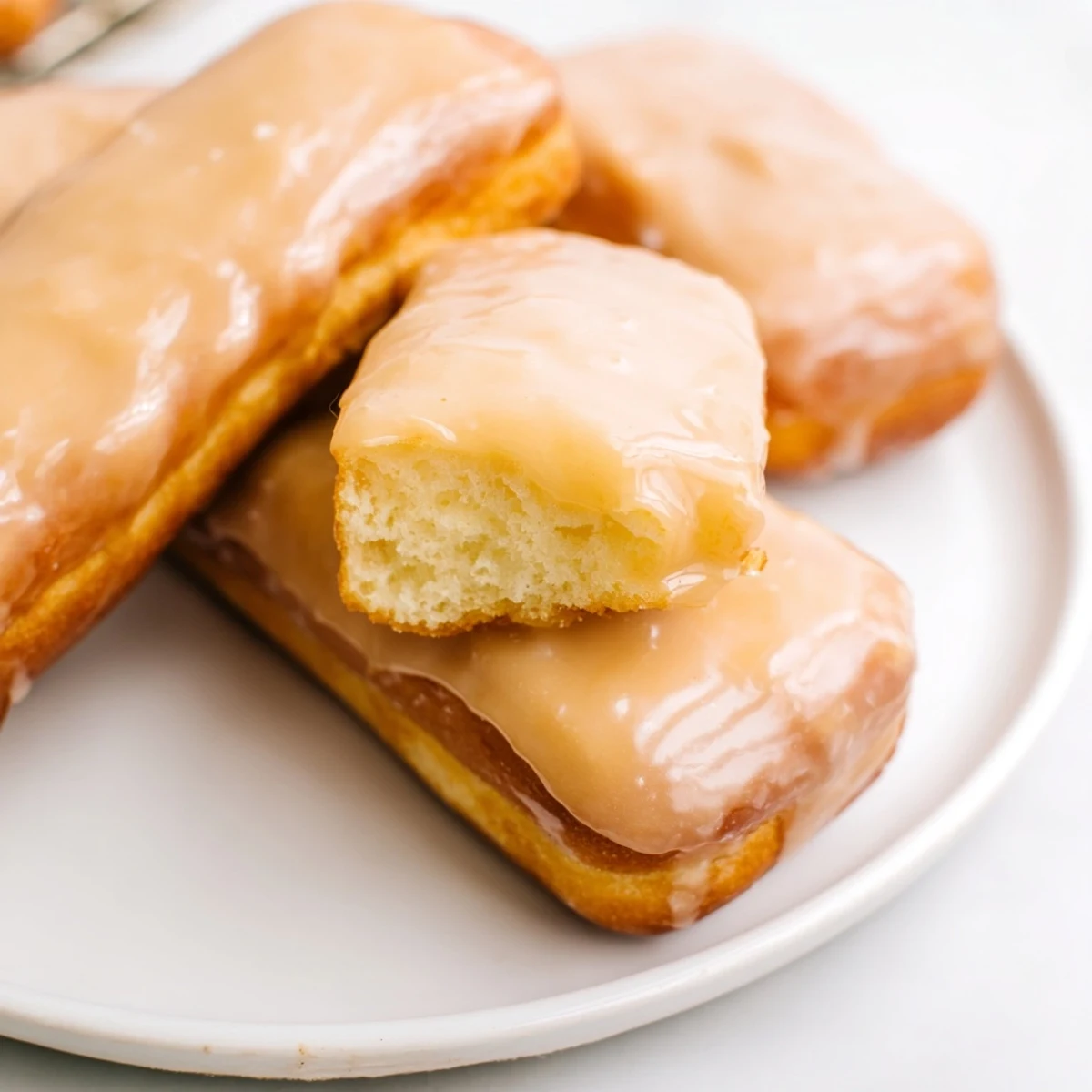 Golden Maple Donut Bars with thick maple glaze are displayed on a wire rack, slightly warm and perfect for breakfast.