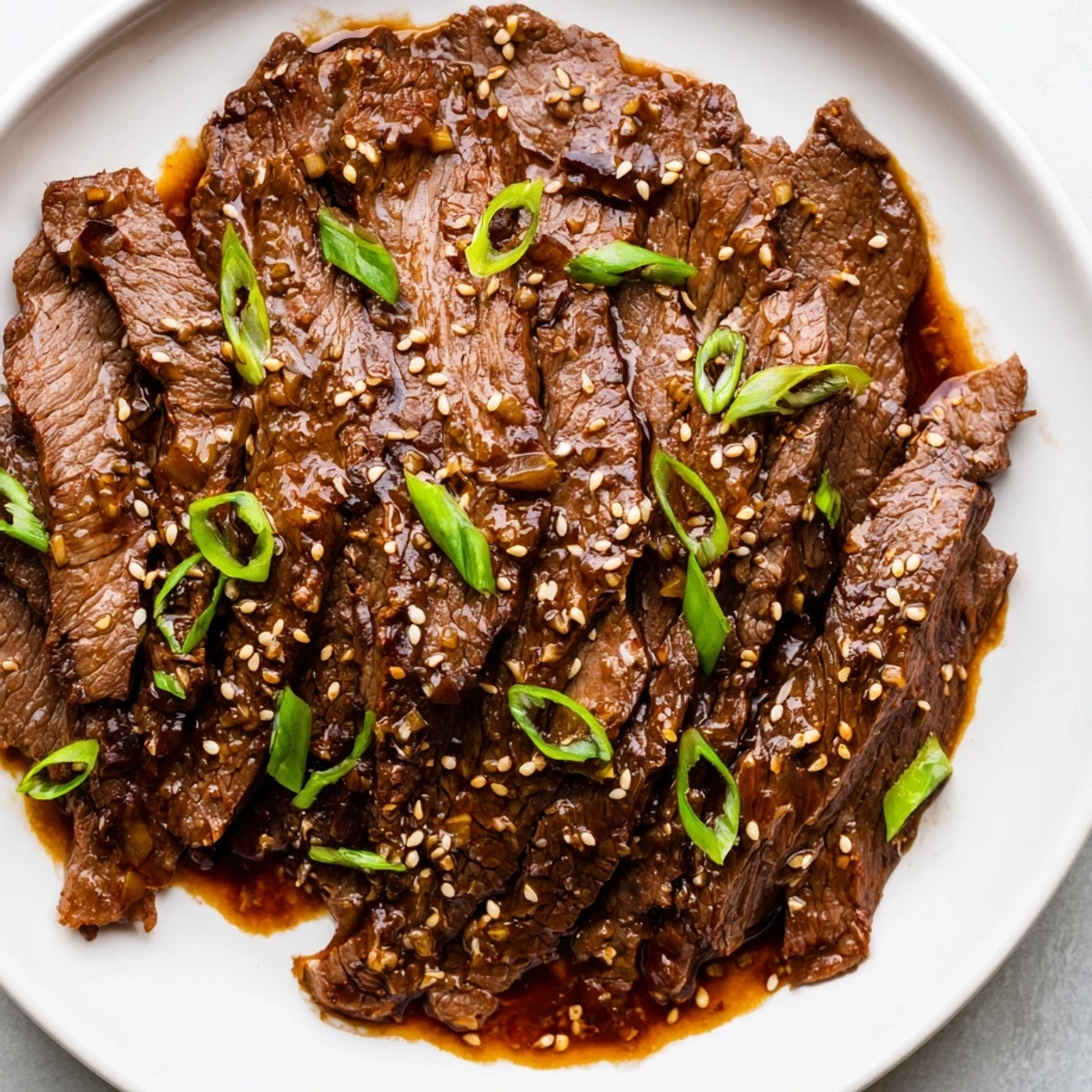 Tender Ultimate Slow Cooker Mongolian Beef with rich glaze served over fluffy steamed rice and garnished with green onions.