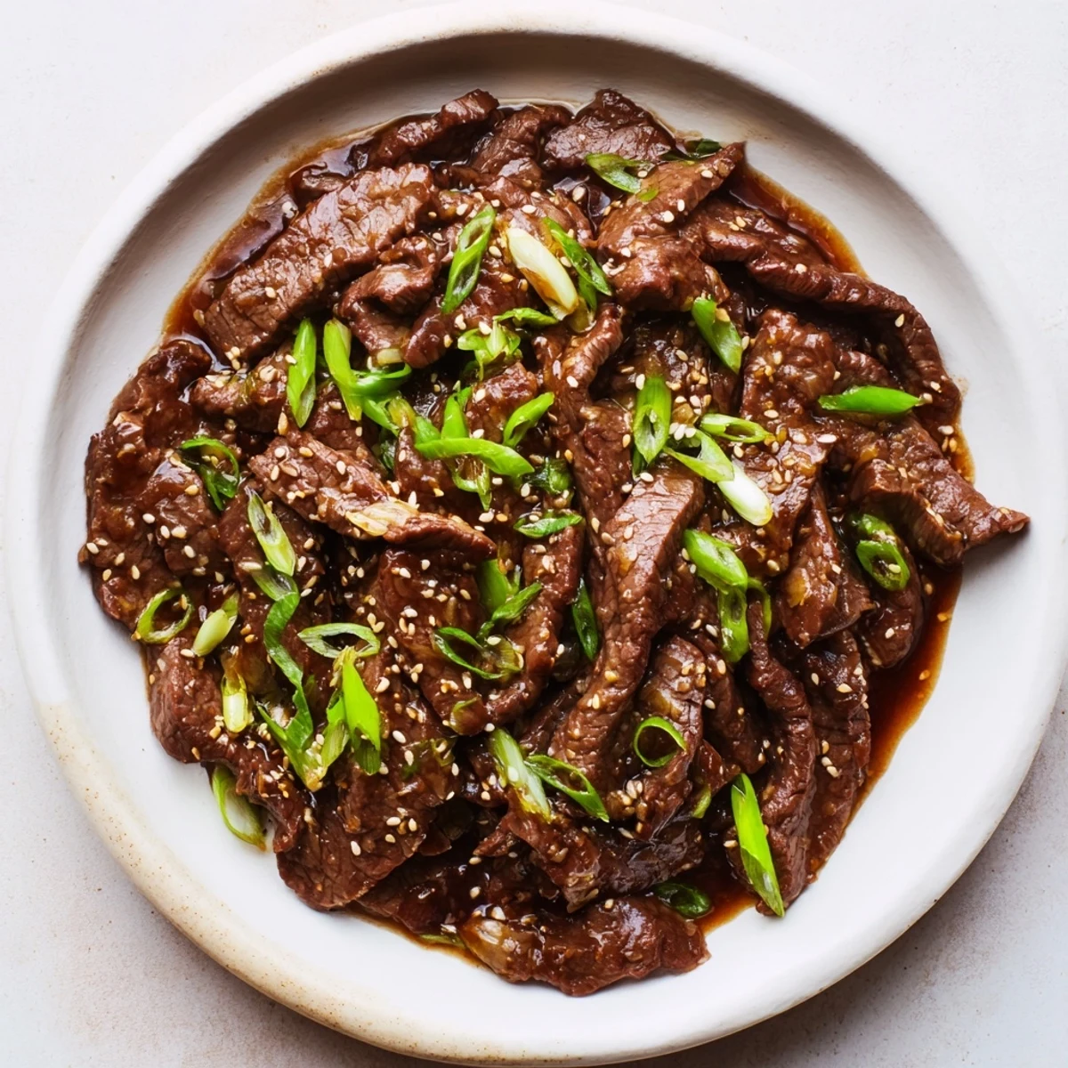 Plated Ultimate Slow Cooker Mongolian Beef beside jasmine rice and broccoli, garnished with green onions for a colorful family-style meal.