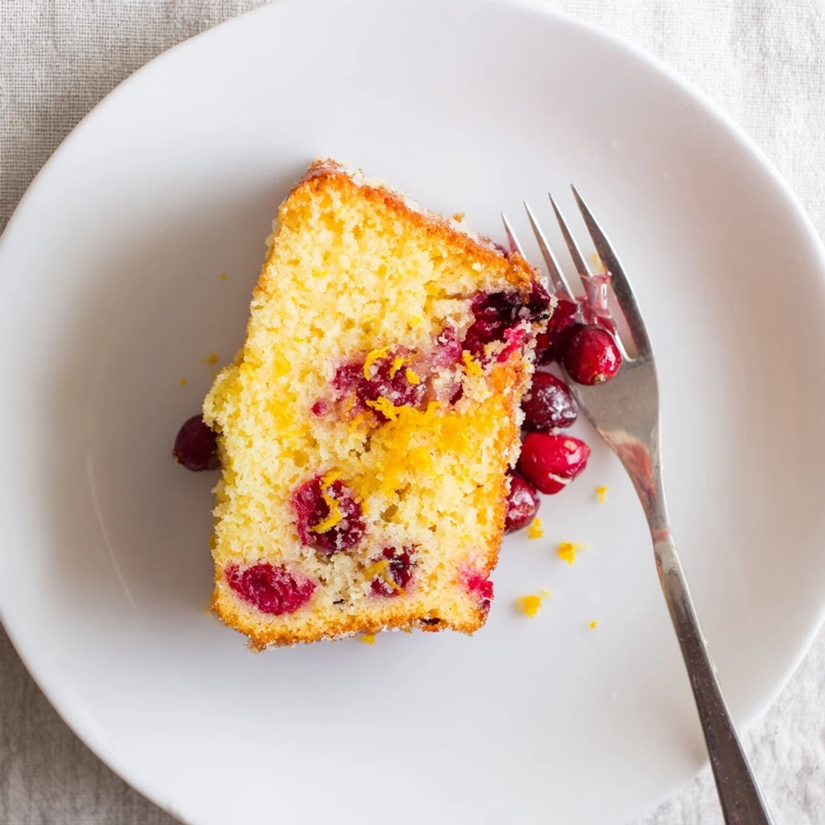 Freshly baked cranberry cake with vibrant red berries visible through a golden-brown crumb top. 
