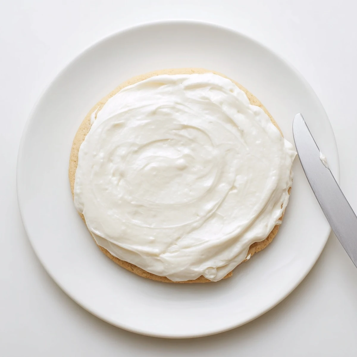 A bowl of Easy Sugar Cookie Frosting with a soft, glossy finish, ready to be spread on decorated cookies.  