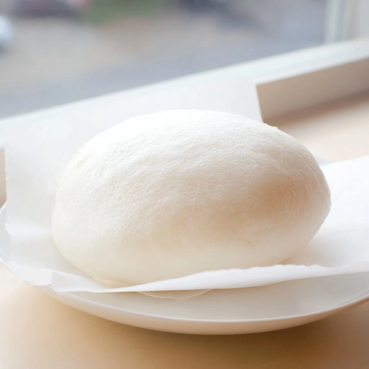 Warm Banh Bao buns steam gently, showcasing fluffy white dough and savory pork filling ready to eat.