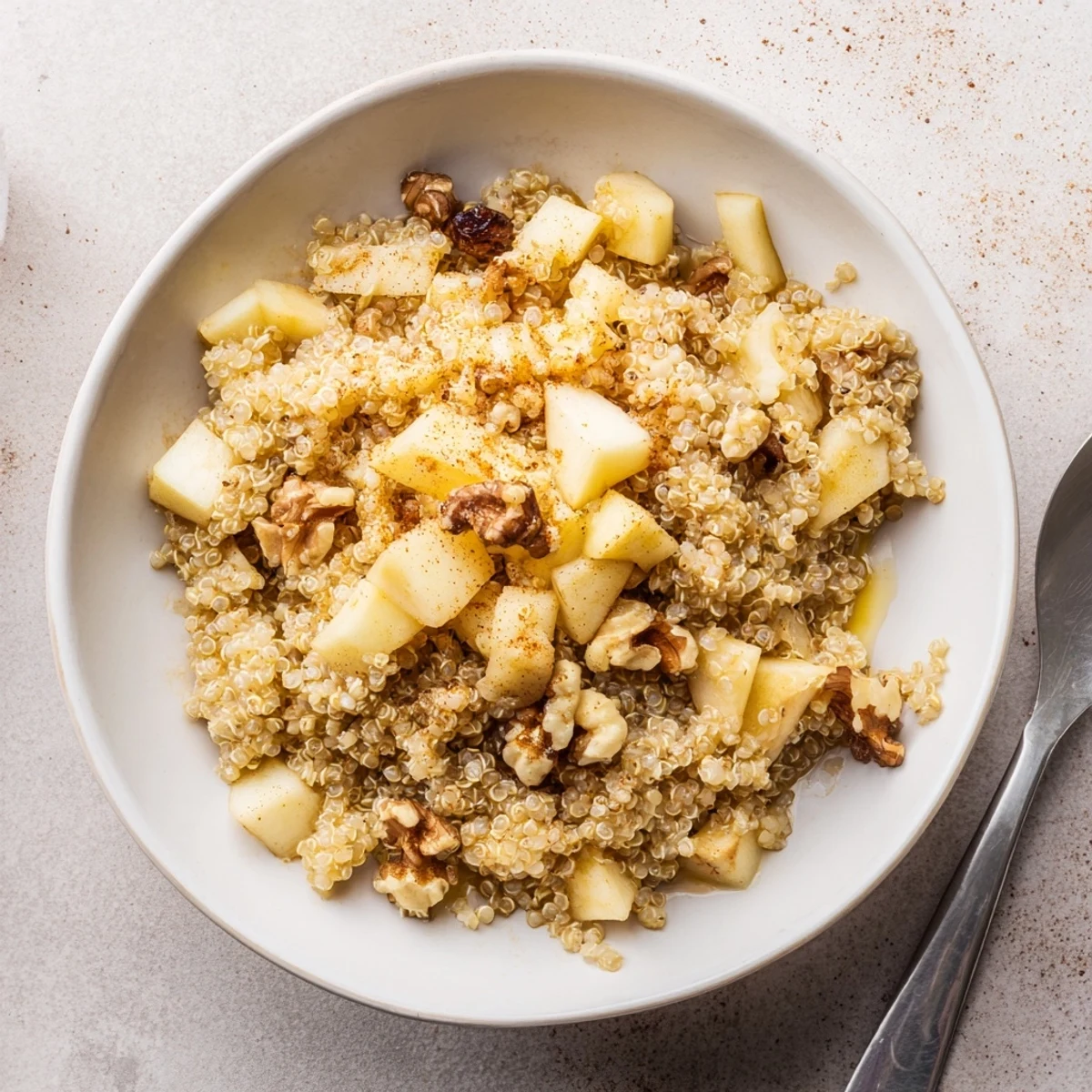 A warm bowl of Healthy Quinoa Apple Breakfast with fluffy quinoa and tender cinnamon apples topped with crunchy walnuts.