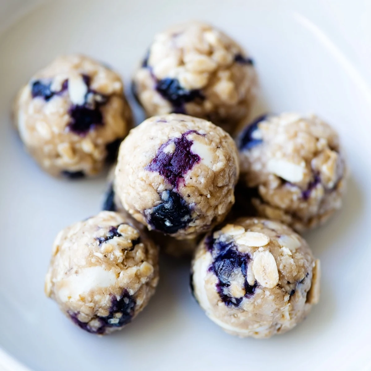 Fresh Blueberry Cheesecake Protein Bites are arranged on a chilled tray, showcasing their creamy texture and speckled berry bits.