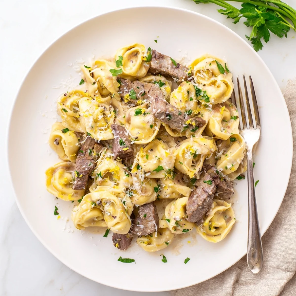 Savory steak and tortellini tossed together in a thick garlic-herb cream sauce with fresh parsley garnish