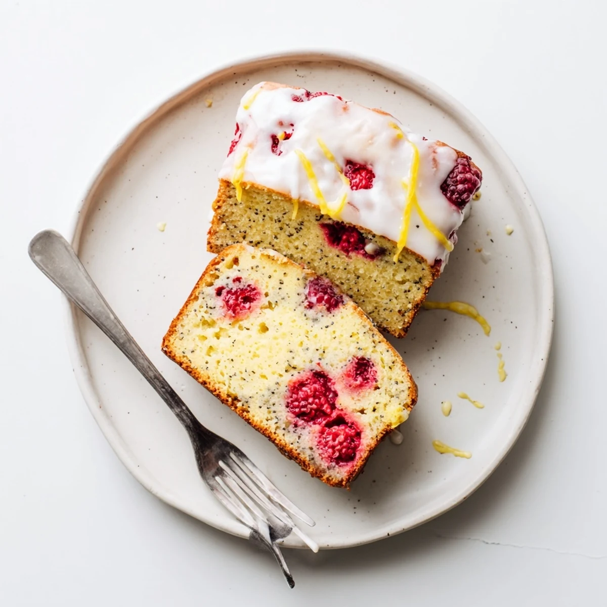 Zesty raspberry lemon poppyseed loaf cake with powdered sugar glaze and fresh berries garnish