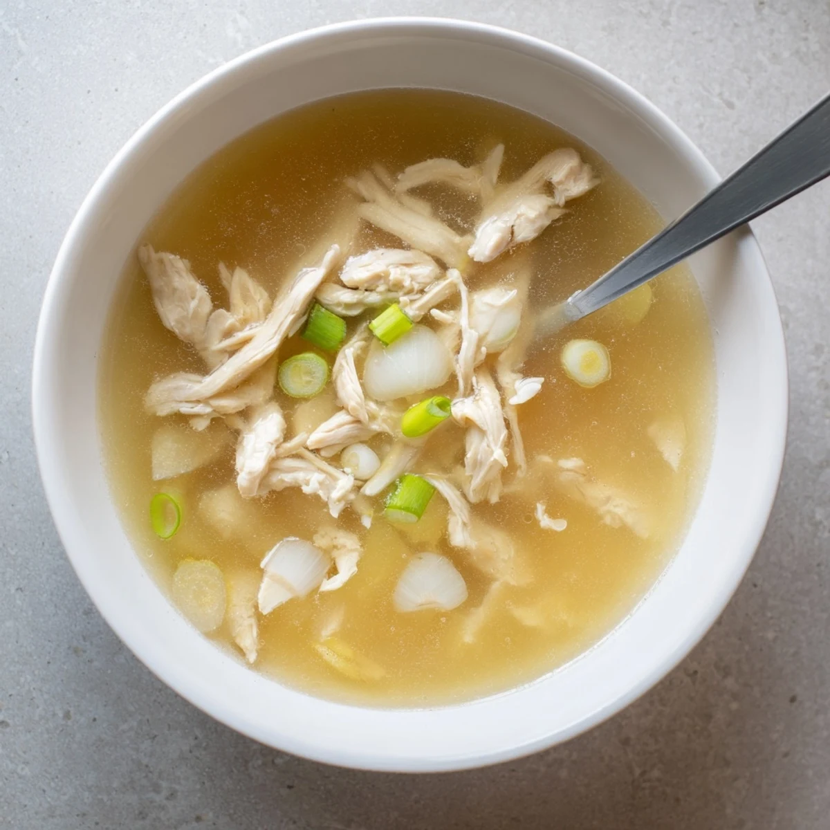 Golden clear broth Dakgomtang featuring tender shredded chicken and aromatic vegetables