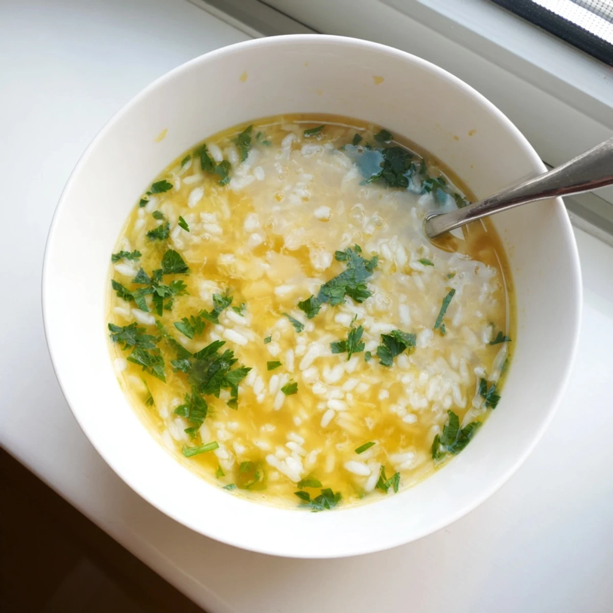 Steaming Greek Egg and Lemon Soup with bright citrus aroma and fluffy rice texture
