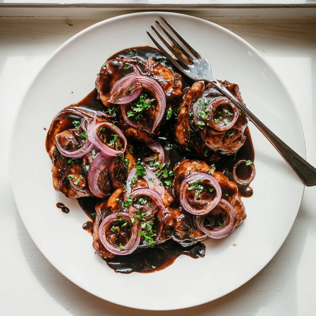 Juicy chicken thighs slow cooked in tangy sweet balsamic vinegar sauce over bed of caramelized onions