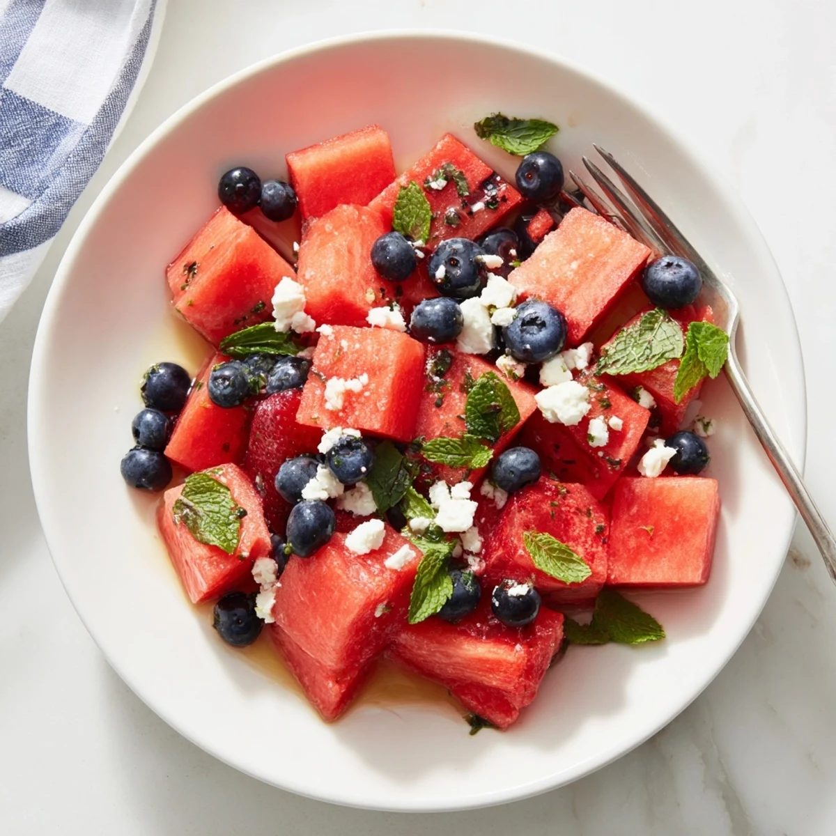 Fresh strawberry watermelon salad with honey lime vinaigrette glistens in a white serving bowl
