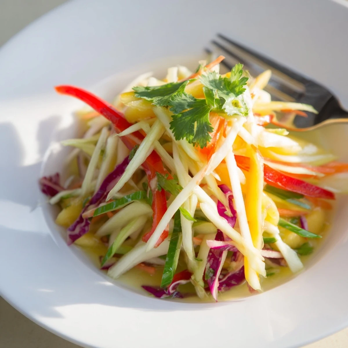 Fresh mango slaw featuring julienned mango, crisp red and green cabbage, and cilantro tossed in tangy lime dressing