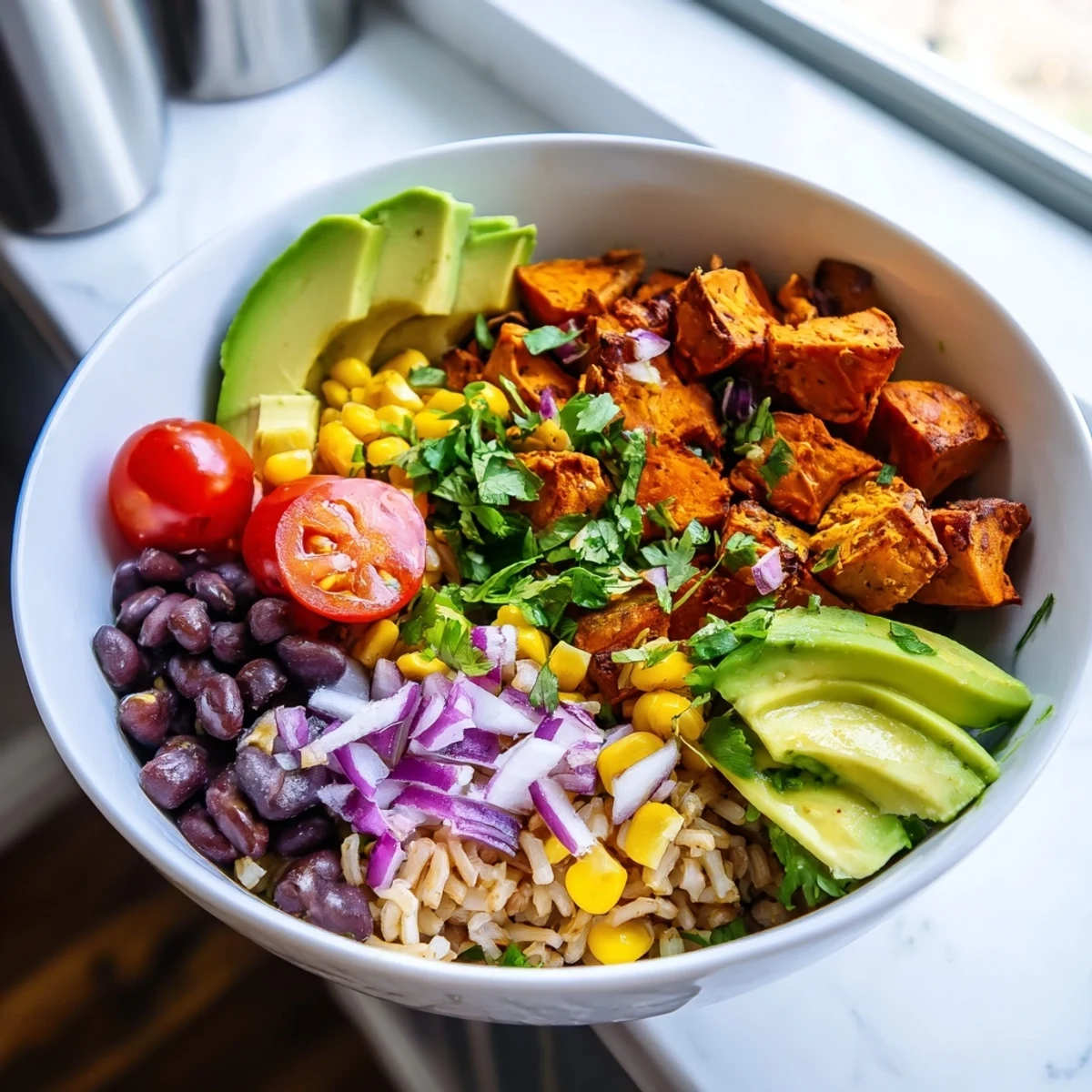 Golden roasted sweet potato vegan burrito bowl topped with black beans avocado and fresh cilantro