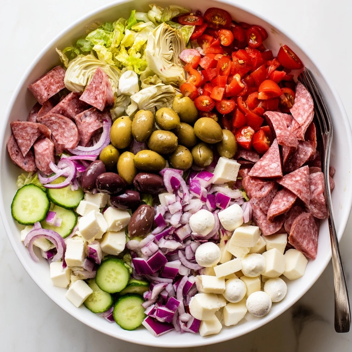 Vibrant Italian antipasti salad featuring artichokes, olives, roasted peppers, and cured meats