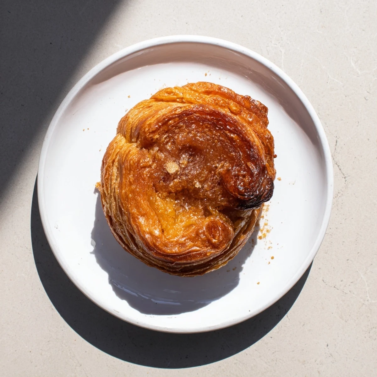 Buttery French Kouign Amann displayed on wire rack with deep amber caramelized crust