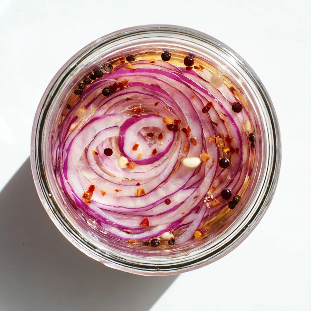 Glass jar filled with vibrant hot honey pickled red onions submerged in sweet brine