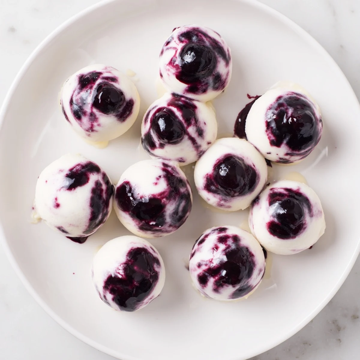 Creamy blueberry swirl yogurt bites with purple berry ribbons swirling through white Greek yogurt frozen on a parchment-lined baking sheet
