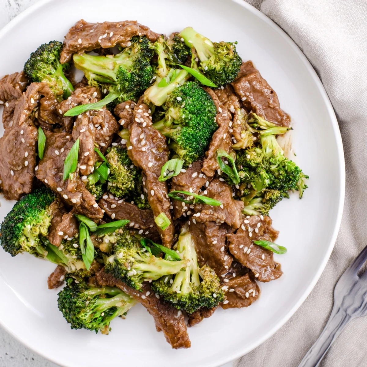 Tender beef strips with crisp-tender broccoli swimming in a savory soy-based glaze in a white bowl