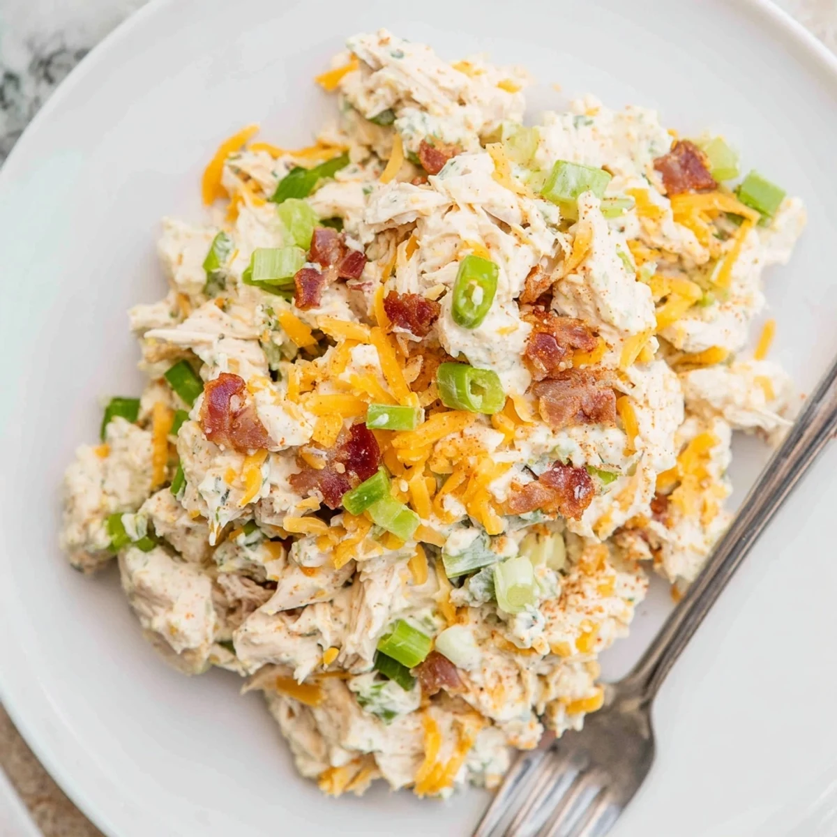 Spicy low-carb chicken salad with cheddar cheese and fresh jalapenos plated on a rustic wooden board