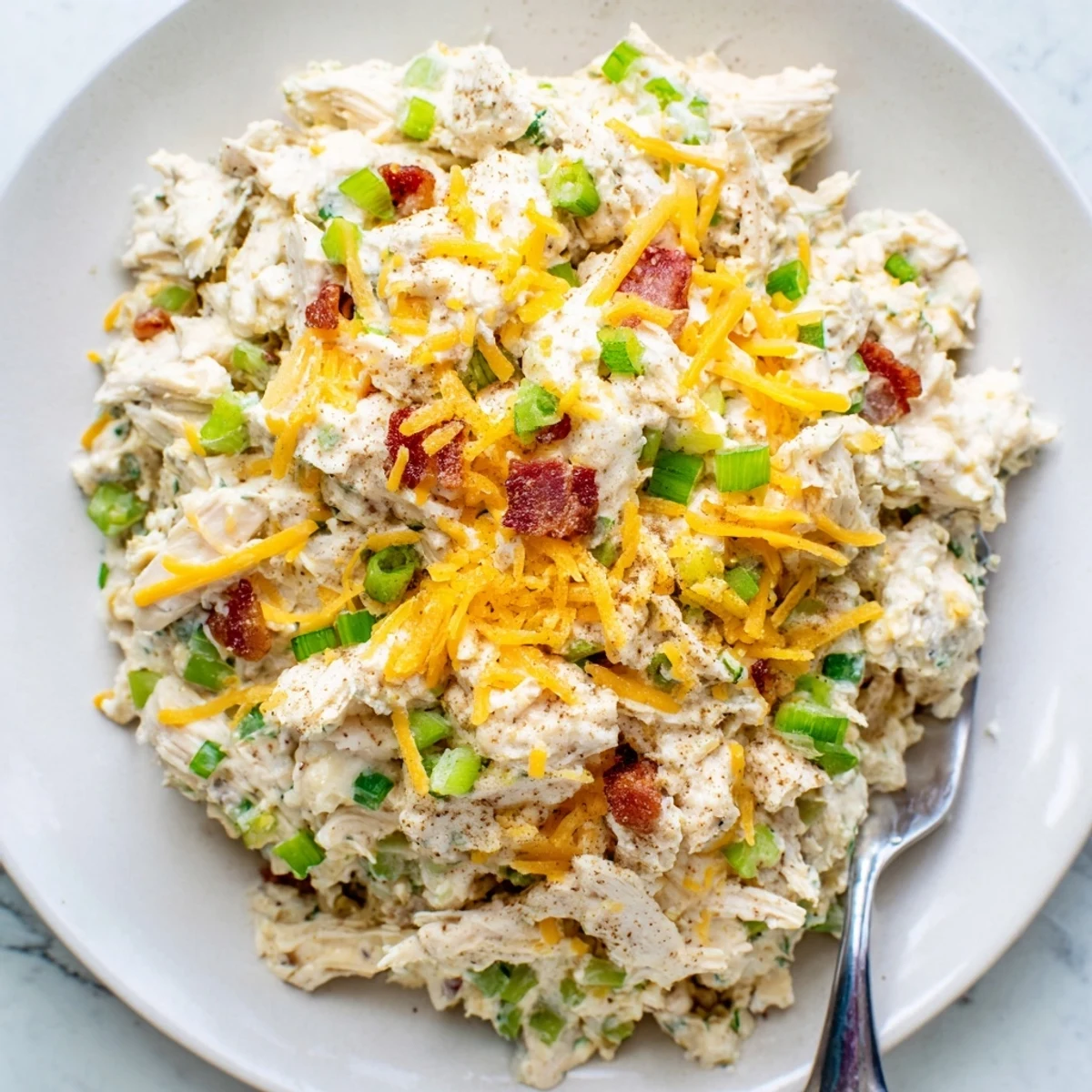 Golden shredded chicken mixed with cream cheese and diced peppers in a colorful keto-friendly lunch bowl