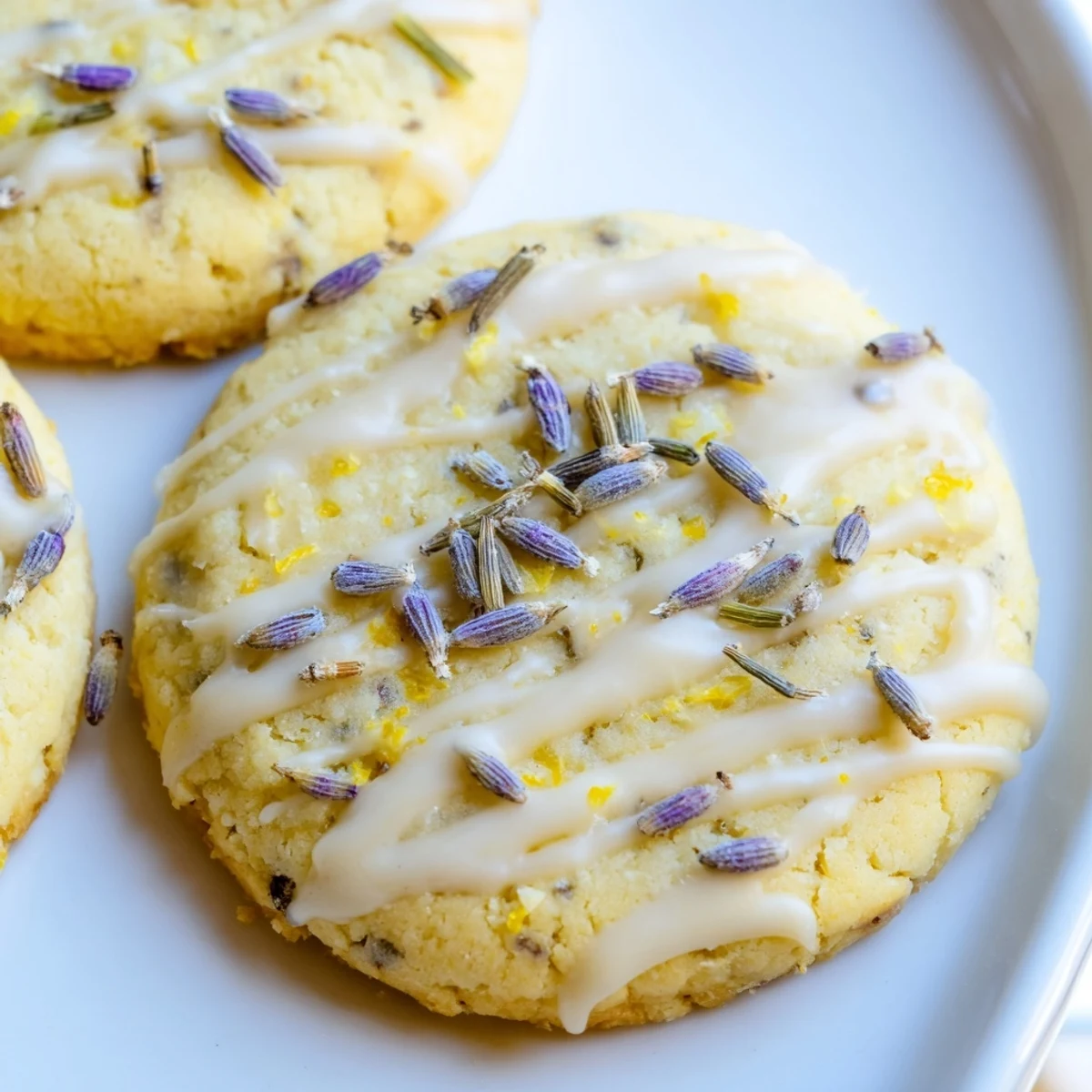 Iced lemon lavender shortbread cookies with glossy icing on a rustic white plate