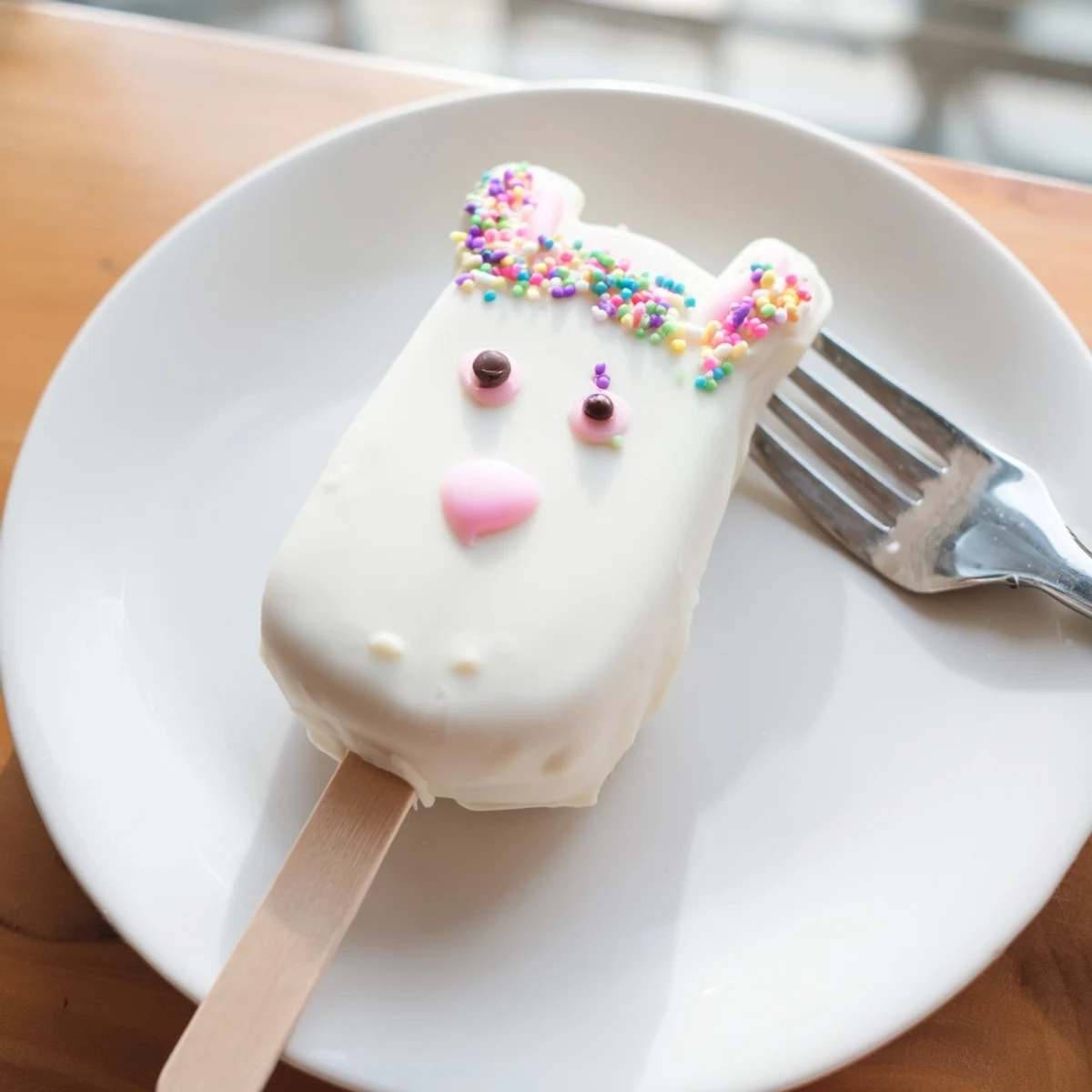 Creamy white chocolate bunny cakesicles decorated with sprinkles for festive Easter dessert display