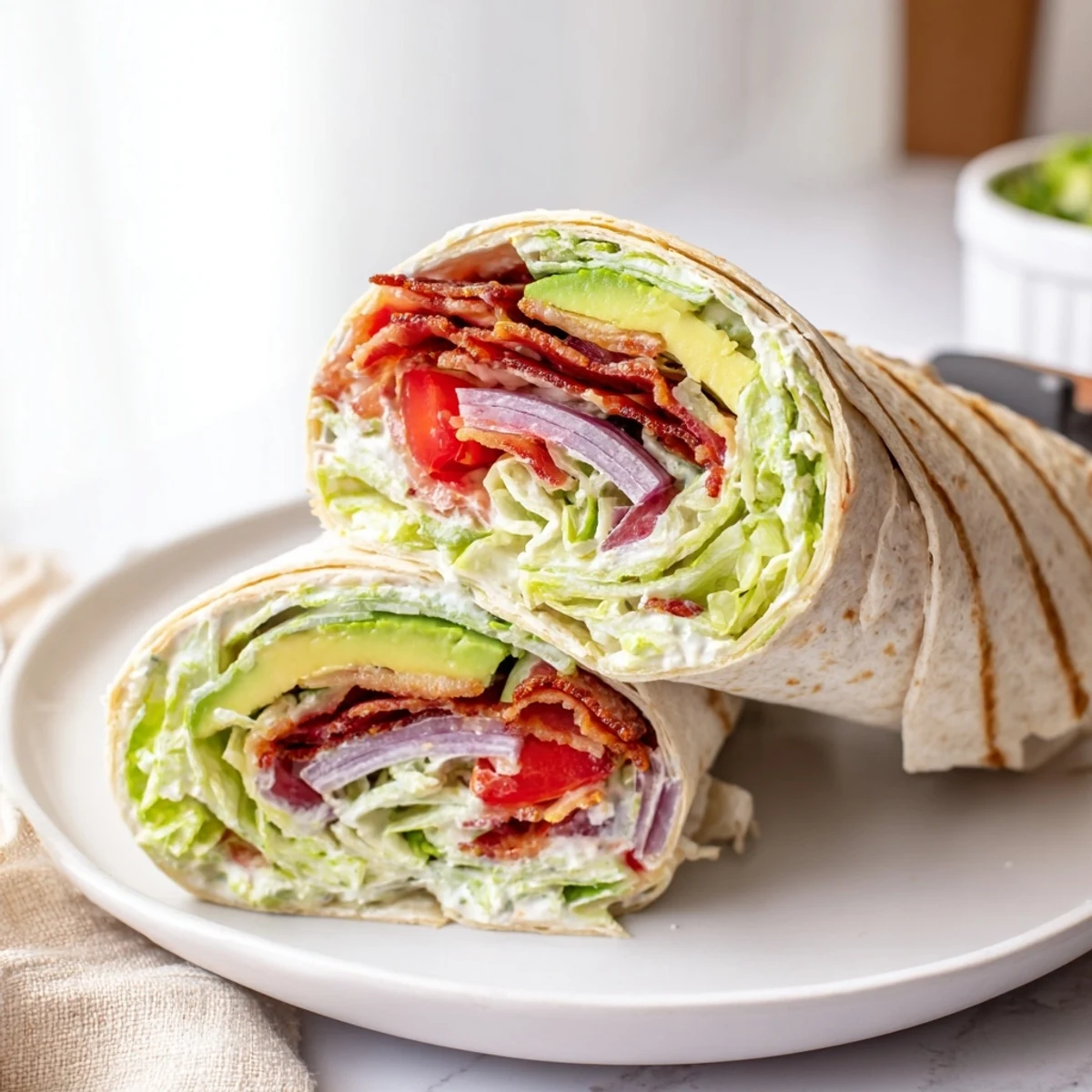 Sliced Meal Prep BLT Wraps on cutting board, revealing crunchy lettuce, avocado