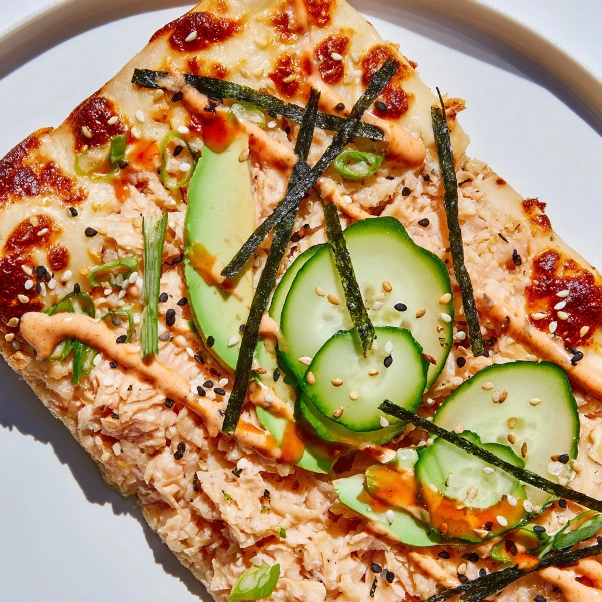 Golden flatbread pizza loaded with seasoned salmon rice, melted cheese, and cucumber toppings