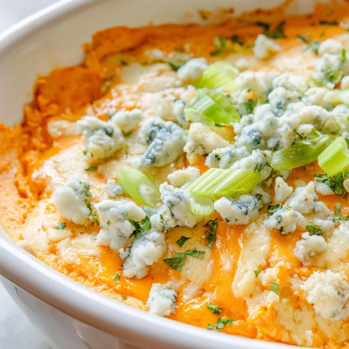 Creamy white bean buffalo dip topped with green onions and crumbled blue cheese garnish