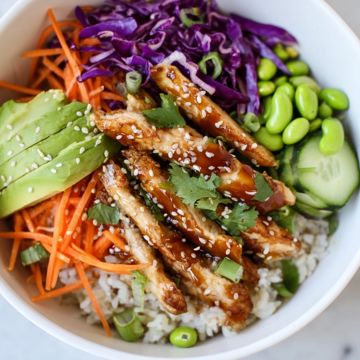 Steaming bowl of Asian Inspired Chicken Power Bowl drizzled with tangy sesame-ginger dressing